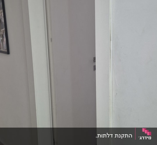 דלת לבנה פתוחה חלקית במסדרון